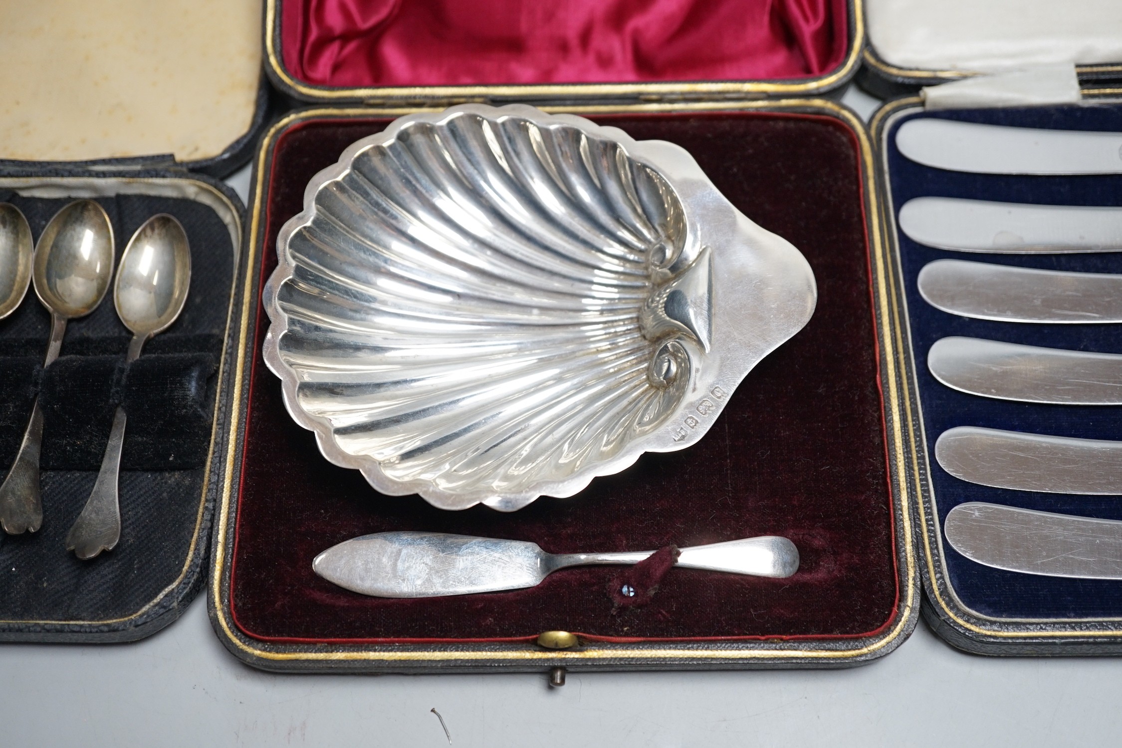 A set of six tea knives, an Edwardian silver butter shell and knife and a set of six silver coffee spoons, all cased.